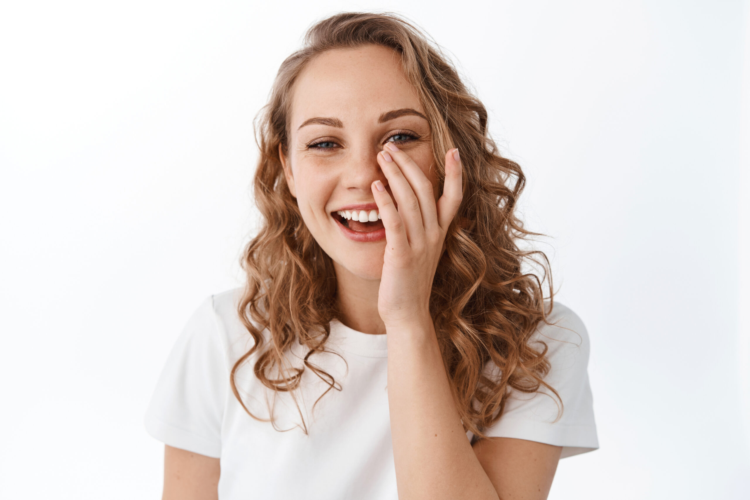 Skin care and women concept. Beautiful smiling woman with natural facial skin without make up, touching face and laughing, standing over white background.